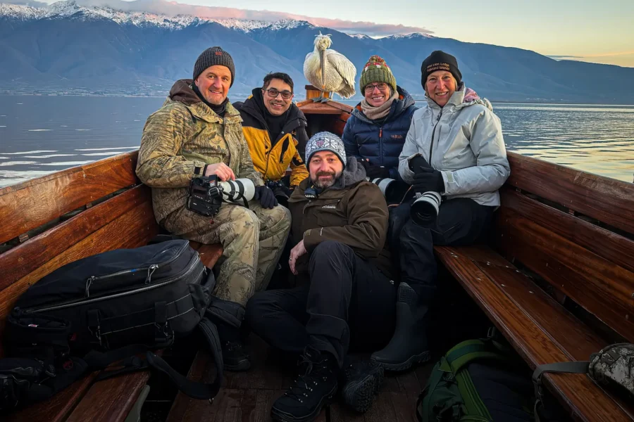 Wildlife photography group on a boat at Lake Kerkini with a Dalmatian Pelican behind them